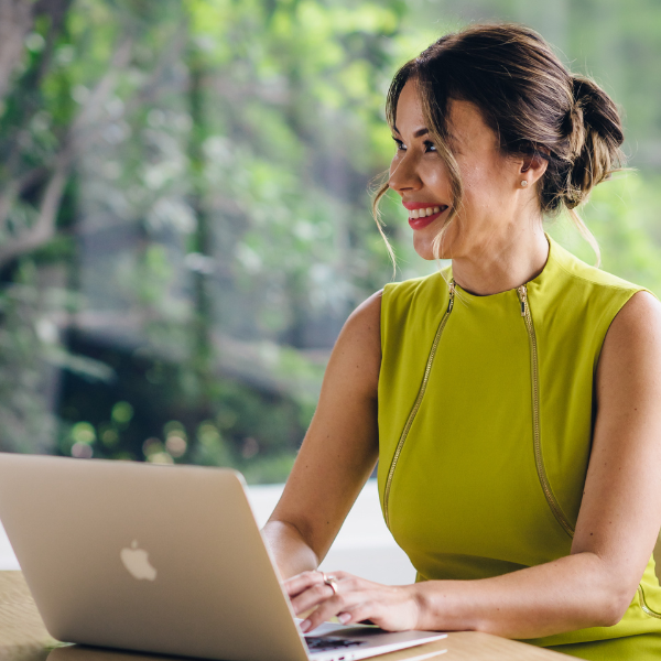 asian professional female founder sitting at a desk with her computer open looking to her right she is wearing a bright green dress branding image los angeles