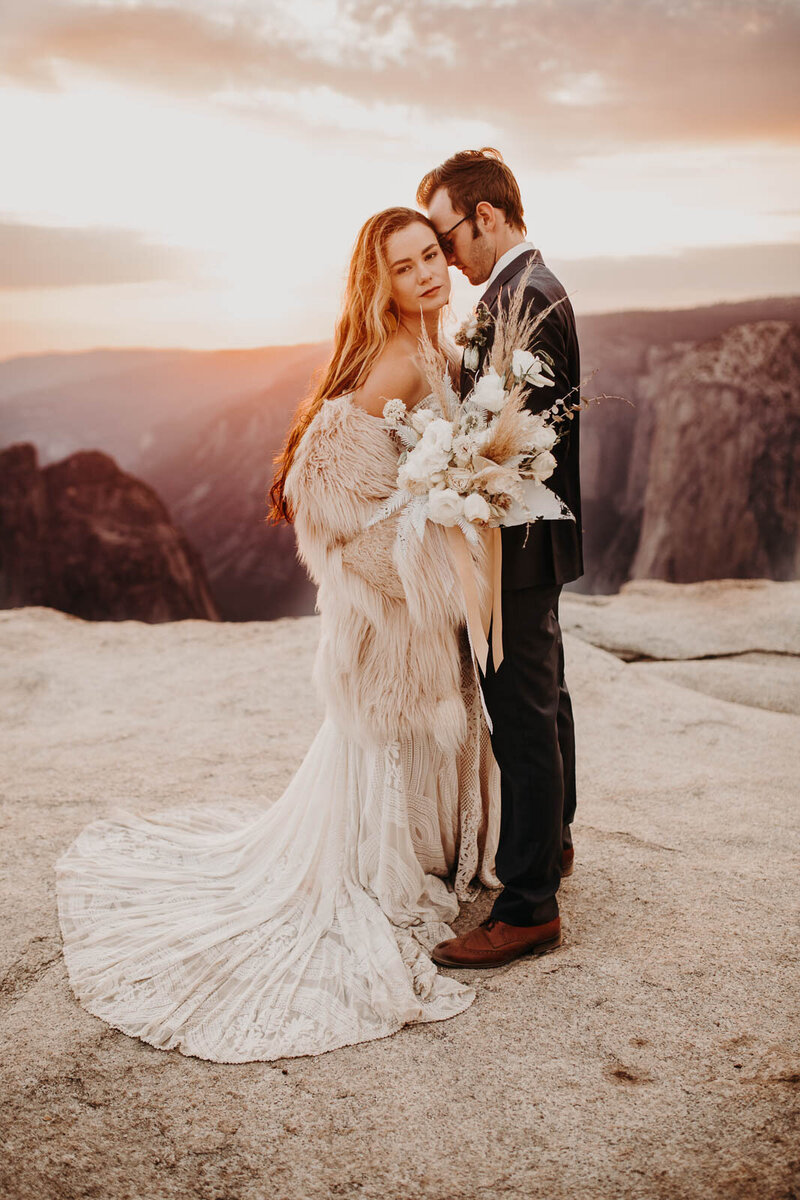 Bride and groom embrace at the edge of Taft Point, surrounded by cliffs and golden light during their intimate Yosemite elopement