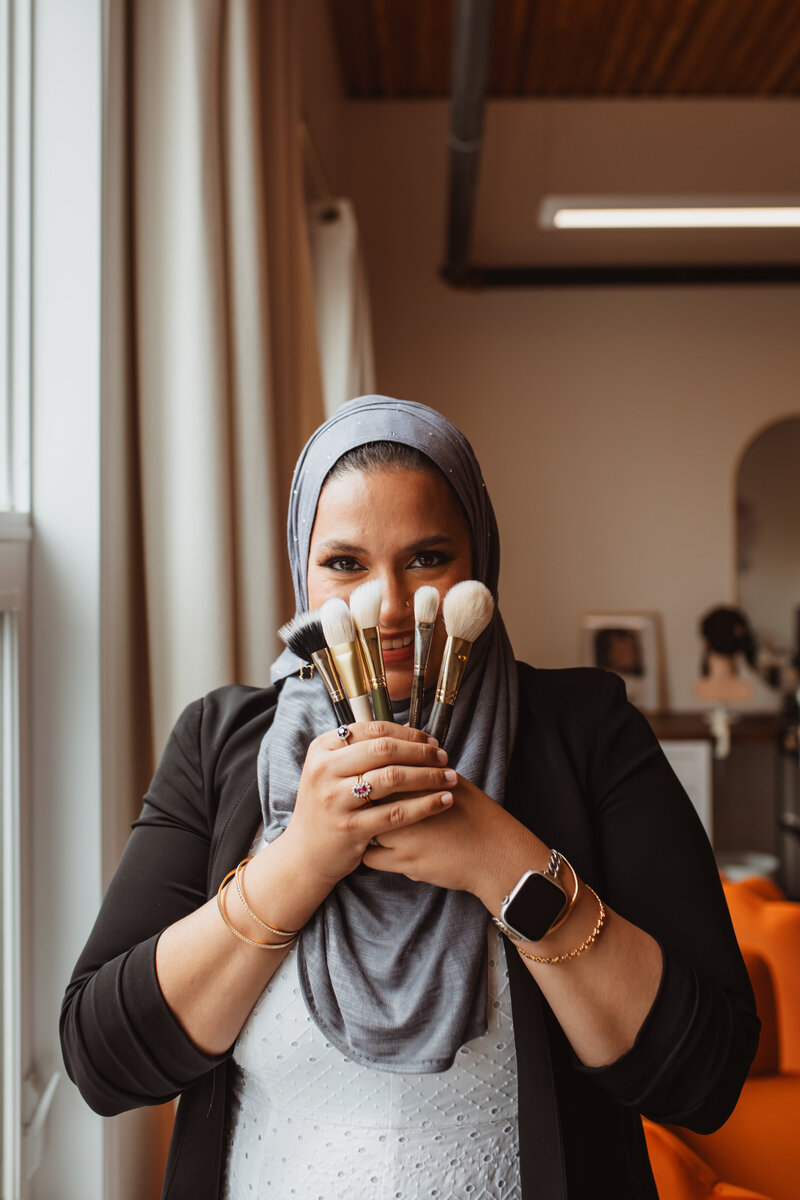 Maya holding makeup brushes and soft glam essentials