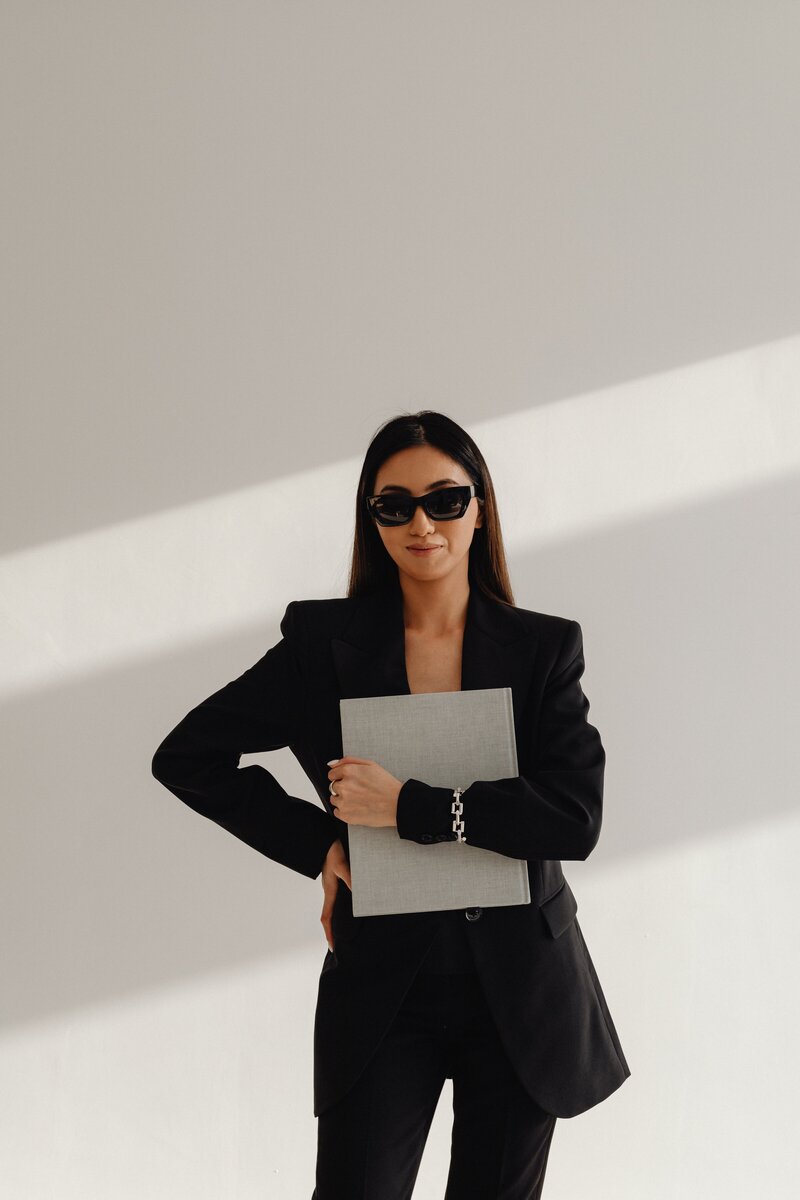 kaboompics_dark-classy-aesthetic-fashion-beautiful-asian-female-entrepreneur-in-black-suit-technology-and-devices-iphone-laptop-airpods-30060-min