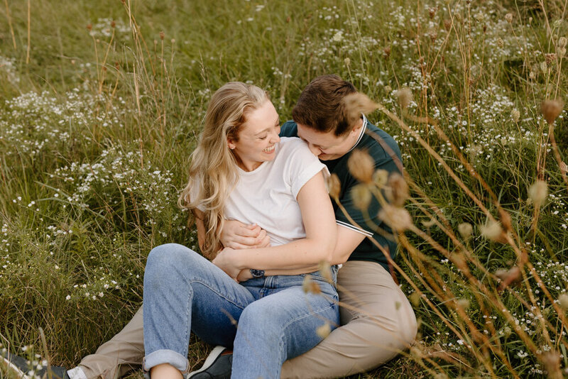 A couple laughs while sitting in tall grass