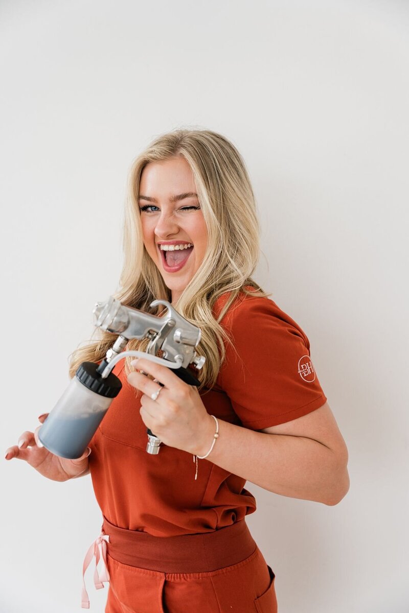 Esthetician holds a spray tan gun