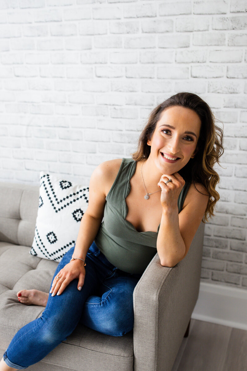 Payton Bendure, social media for small business, sitting on couch wearing a green shirt and jeans