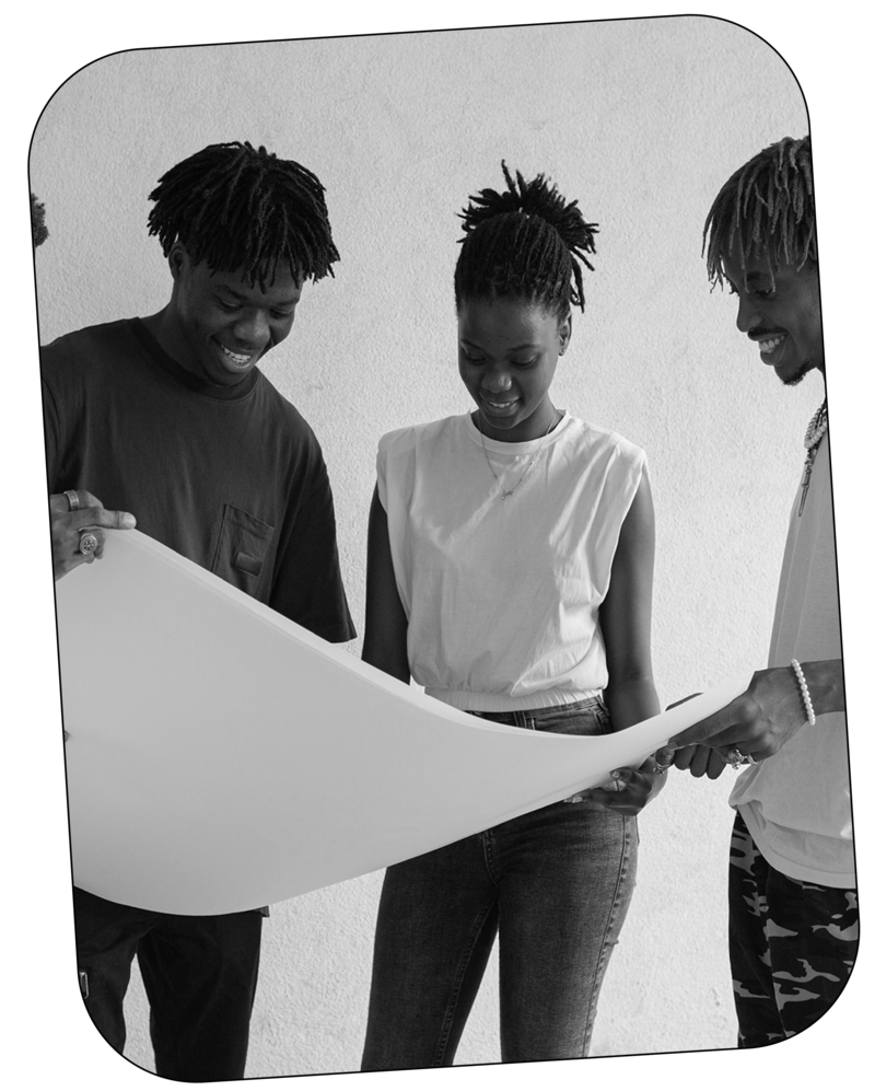 Black and white image of teenagers smiling and looking at a poster board
