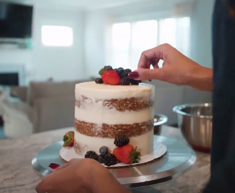a person putting berries on the top of a small cake 