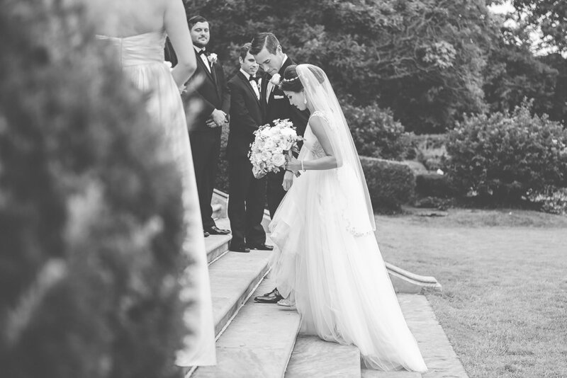  bride walks calmly through her wedding ceremony, captured candidly in black and white with her bouquet in hand and guests looking on.
