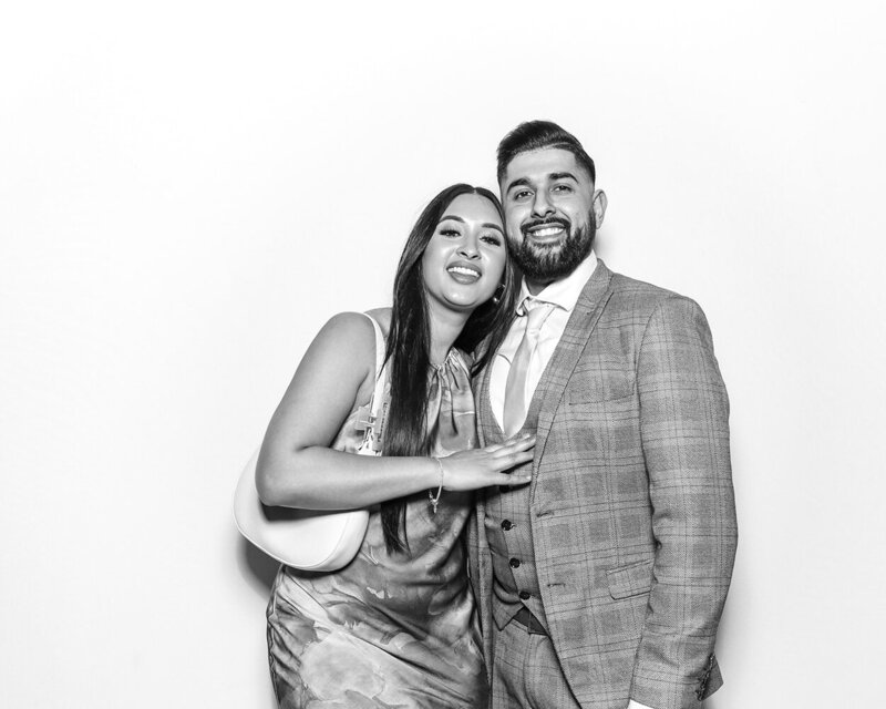 Black and white filter for a print with a couple posing against a white backdrop, during a an Asian wedding party celebration, for Mad Hat Photo Booth