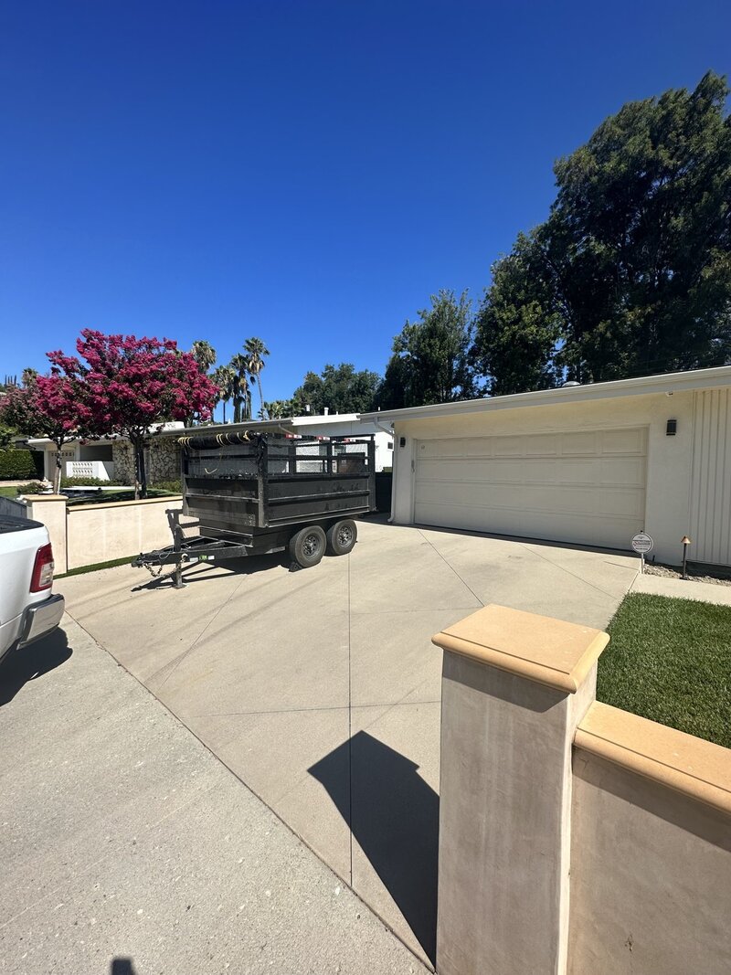 A dumpster trailer placed in front of a residential garage