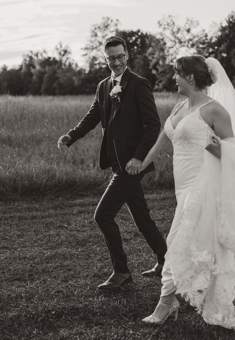 Candid moment of newlyweds walking through the grounds of The Little Chapel at Haven Ridge, captured in a documentary style during their Winston-Salem wedding.