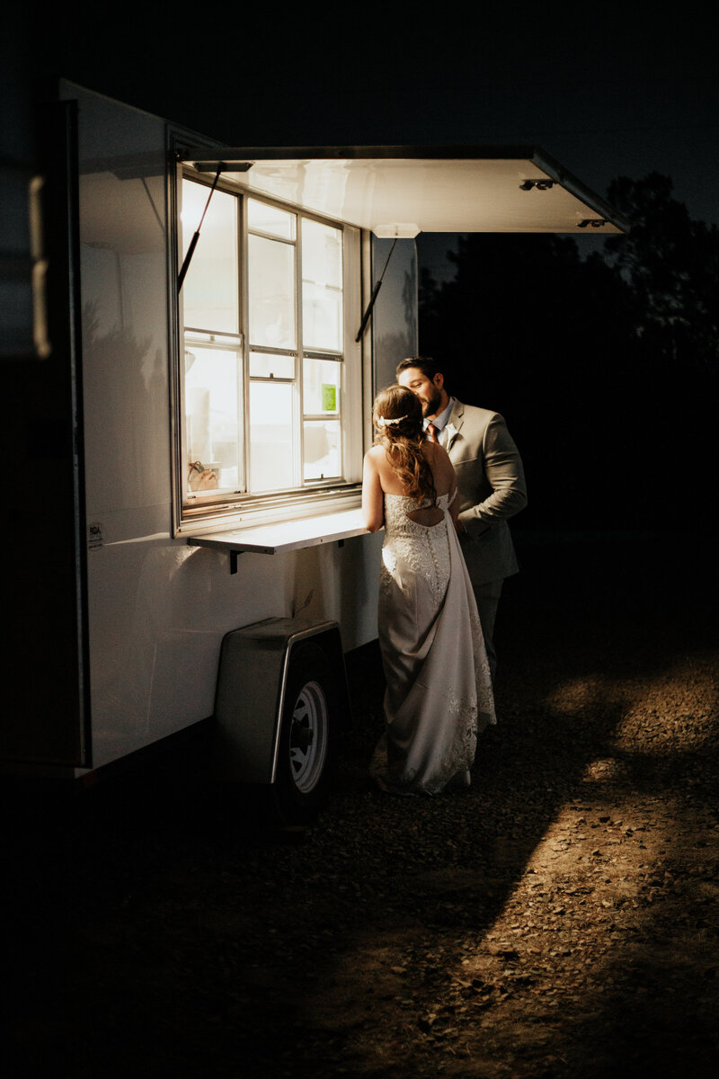 bride and groom kissing in front of window