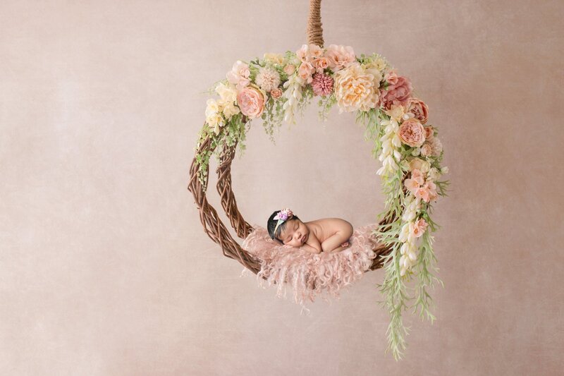 Newborn baby sleeping on beautiful floral hoop swin