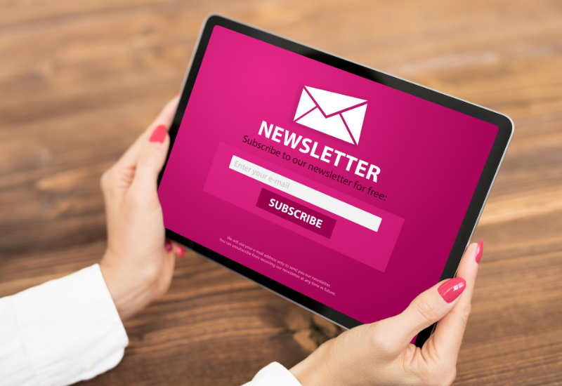Two hands hold a tablet device displaying a newsletter optin form. In this blog on creating an email marketing strategy for your femtech startup, Copywriter Redacted suggests placing optin forms on your website.