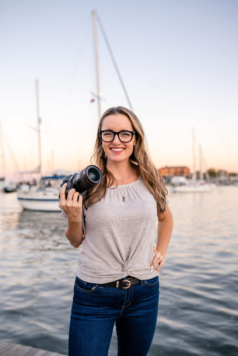 Kelly Eskelsen smiles with a camera at sunset on Annapolis City Dock.