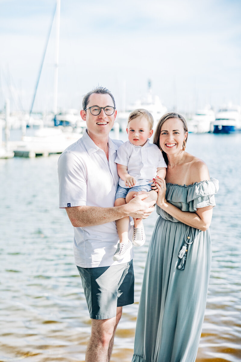 Smiling families enjoying a holiday photoshoot with sea grapes and sailboats in view.