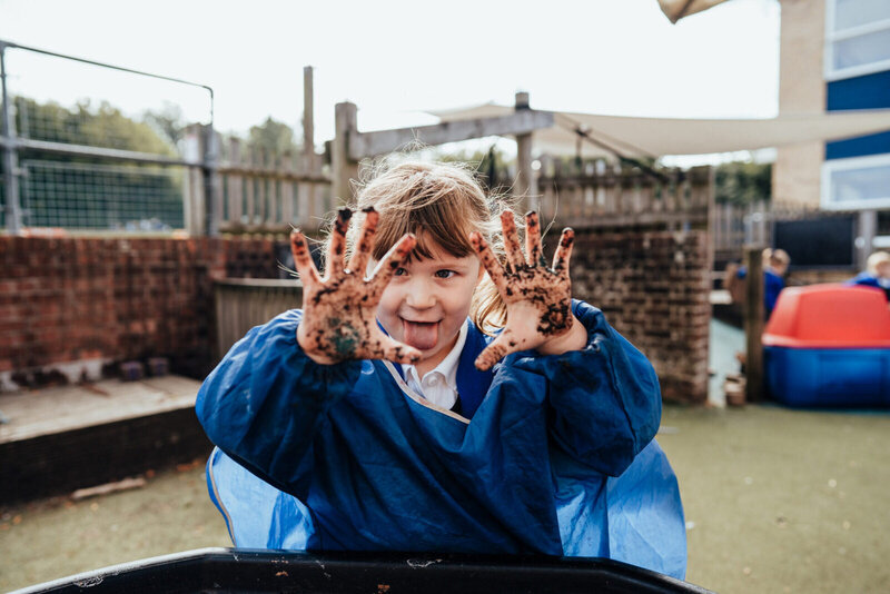 school girl playing in mud on playground - St Johns COE school, Hampshire