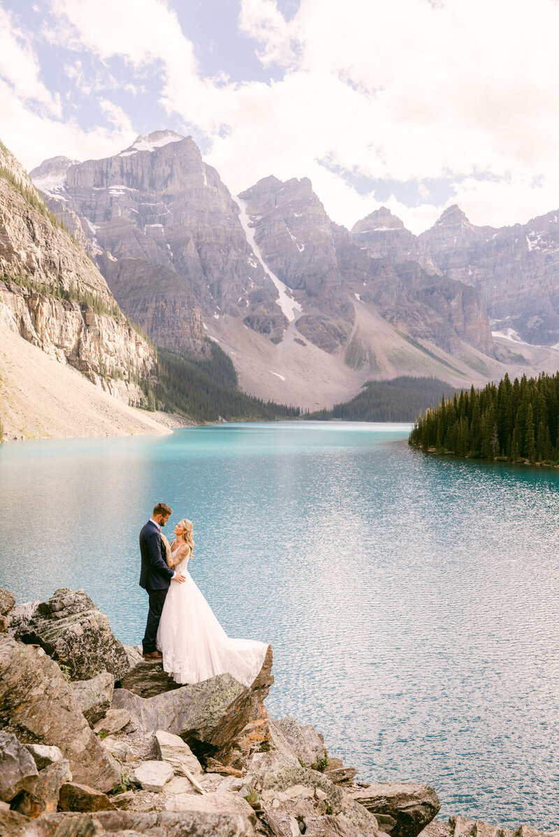 Bride and Groom Embrace on Rock at Moraine Lake Banff National Park