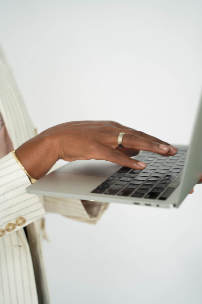 Black career coach for women typing on computer in white stripped blazer