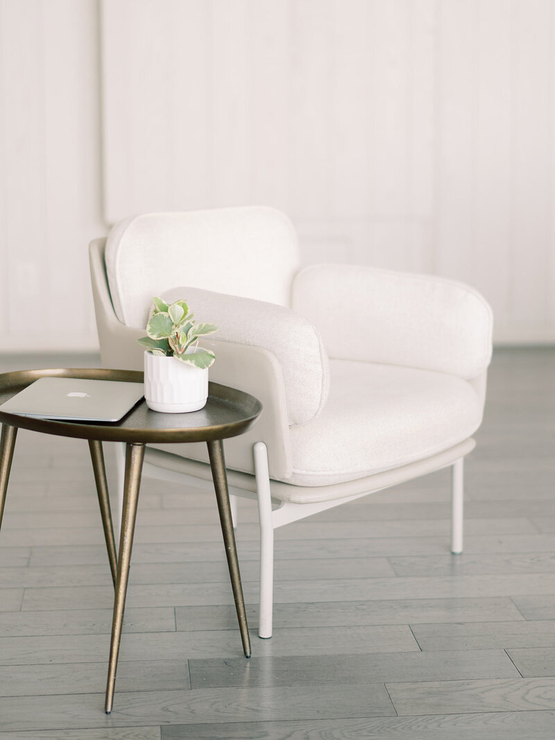 white sofa chair and laptop on side table