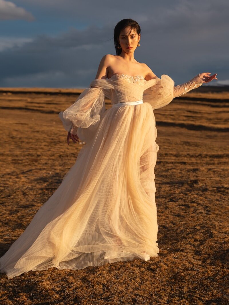 Couture dress bridal shoot on a field with mountains in the background and golden light.