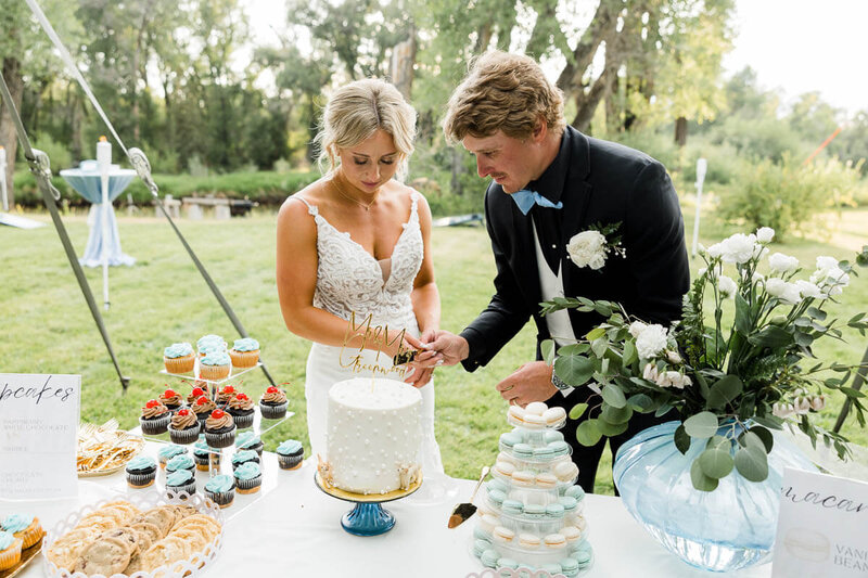 Bride and groom cutting cake at outdoor wedding venue in Saratoga, WY