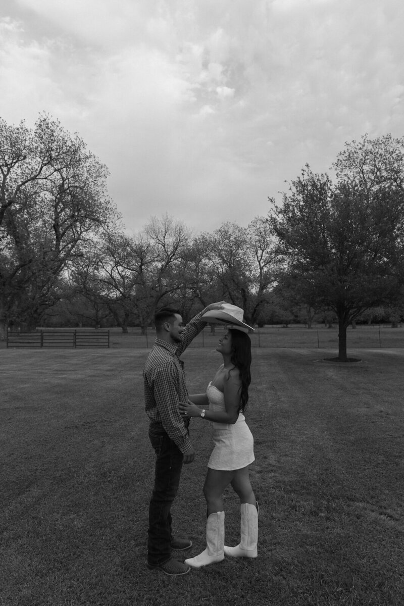 man places hat on girlfriends head during couples photoshoot in texas