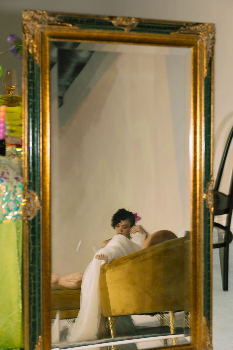 the reflection of a person in a wedding dress sitting on a chair.