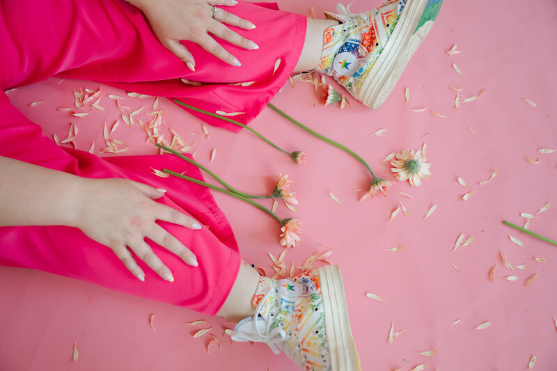 Close up of color shoes and pink pants with flowers on the ground