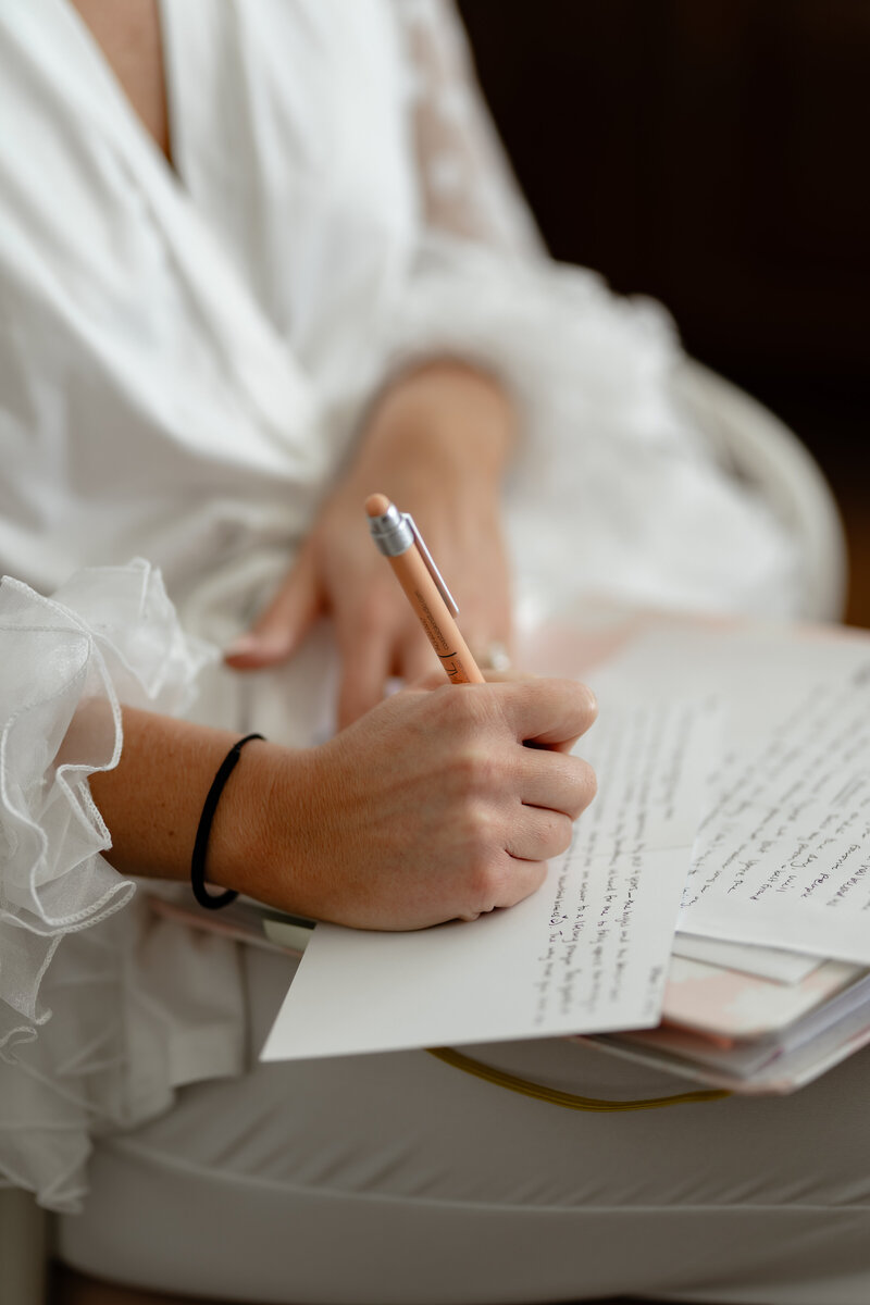 Bride writing her groom a note while she gets ready for her wedding. In white pajamas.