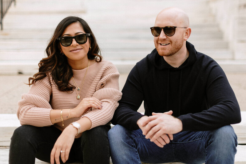  A couple relaxes on steps, sporting sunglasses, basking in the warmth of a sunny afternoon.