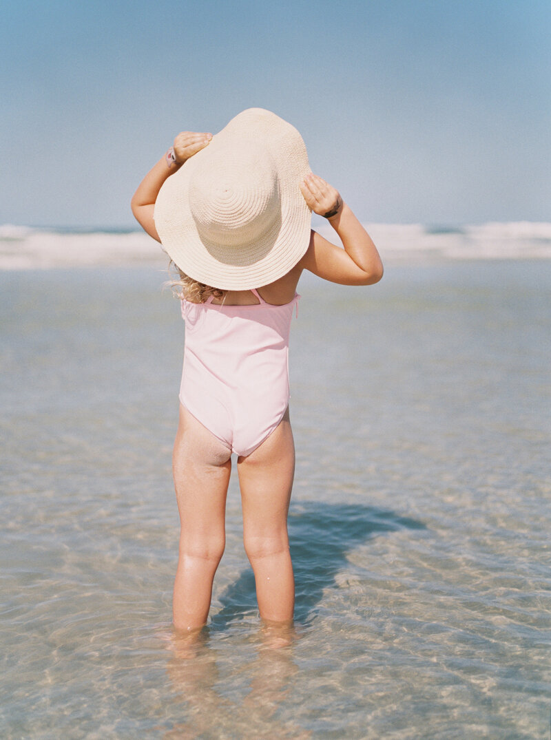 little girl with a hat at the beach by Orlando lifestyle photographer