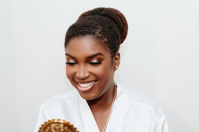 Bride smiling while getting professional makeup and hair done during wedding day preparation at The Mayfair House Hotel.