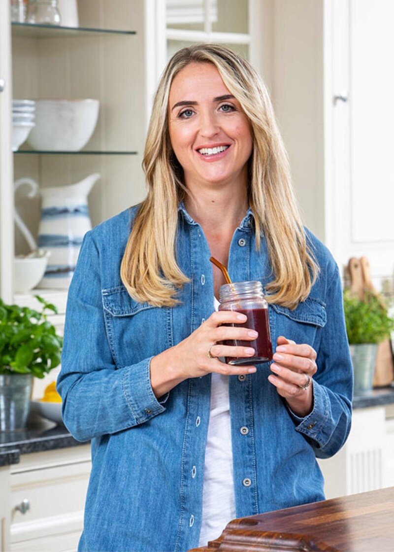 Charlotte Grand in the kitchen holding a smoothie, founder of The Menopause Kitchen, supporting women 40+ with nutrition and functional fitness through perimenopause and beyond.
