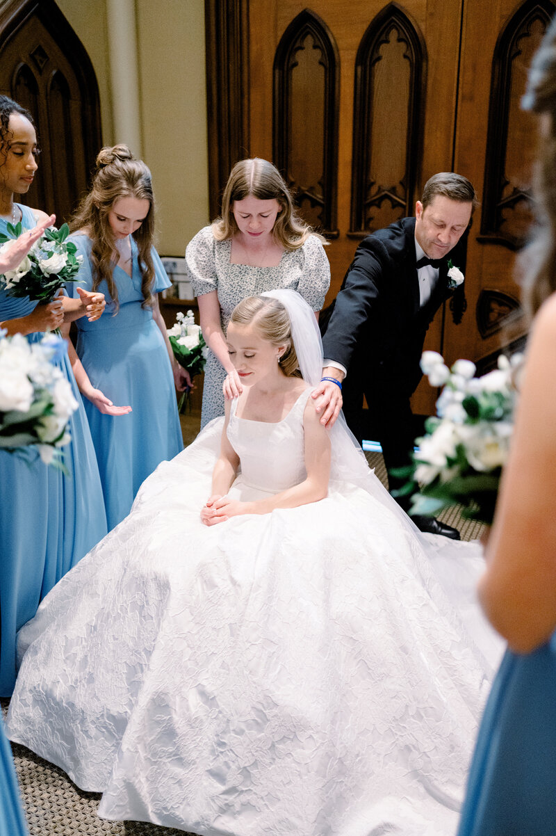 wedding guests praying over a bride