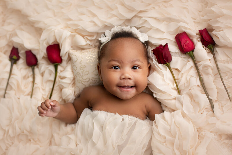1 year old baby posing for milestone portraits with wooden backdrop