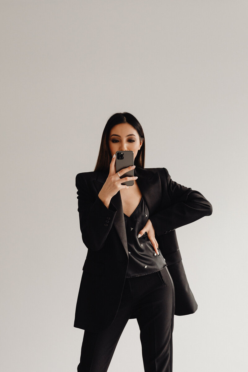 kaboompics_dark-classy-aesthetic-fashion-beautiful-asian-female-entrepreneur-in-black-suit-technology-and-devices-iphone-laptop-airpods-30094