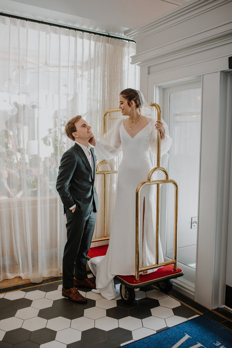 Bride and groom standing on hotel bell cart