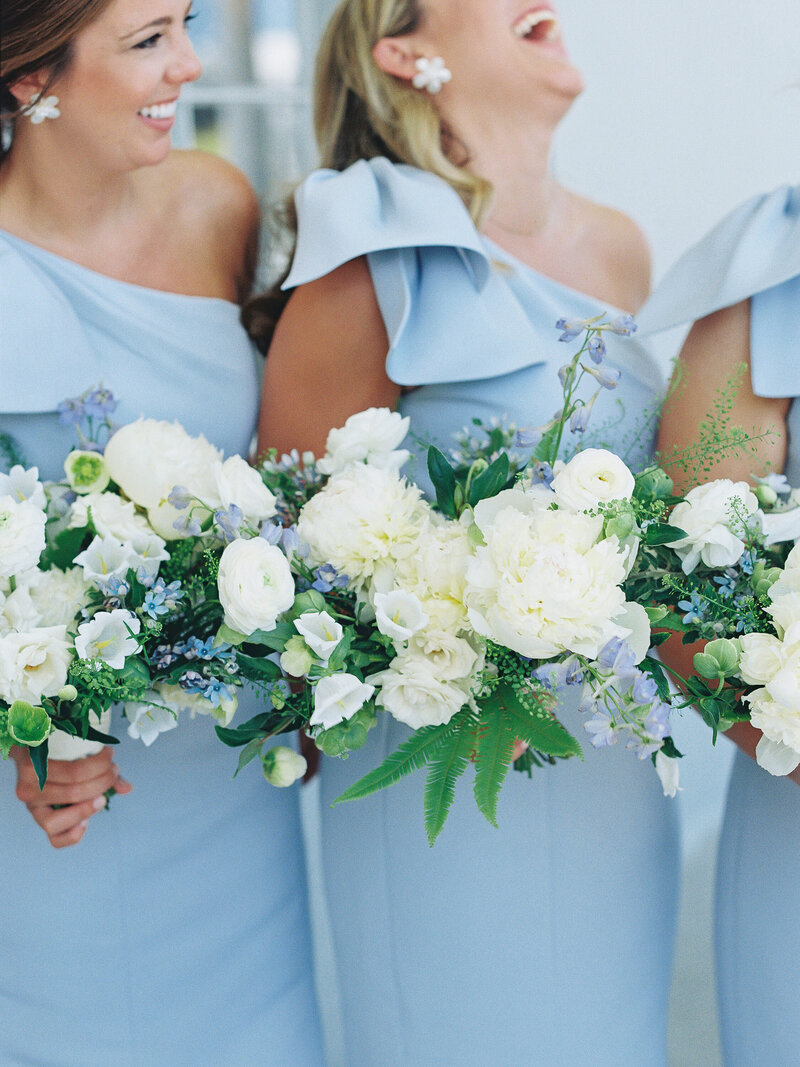 Bridesmaids hold bouquets and laugh