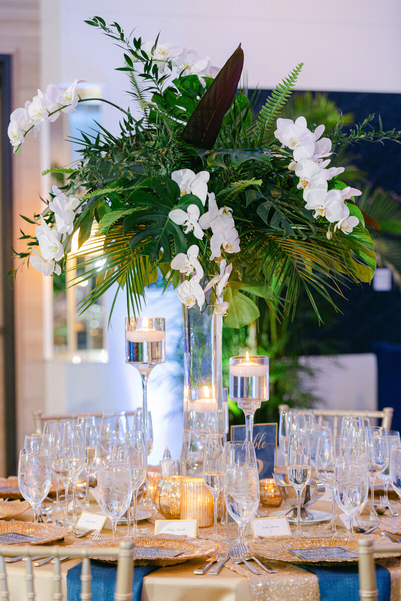 Tall palm branch and white orchid tropical wedding reception centerpiece