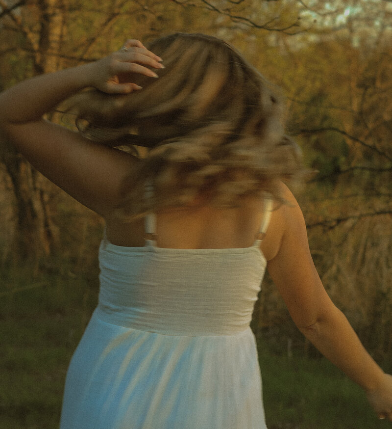 A girl is seen jumping and is caught mid air away from the camera and her hair is flowing beautifully.