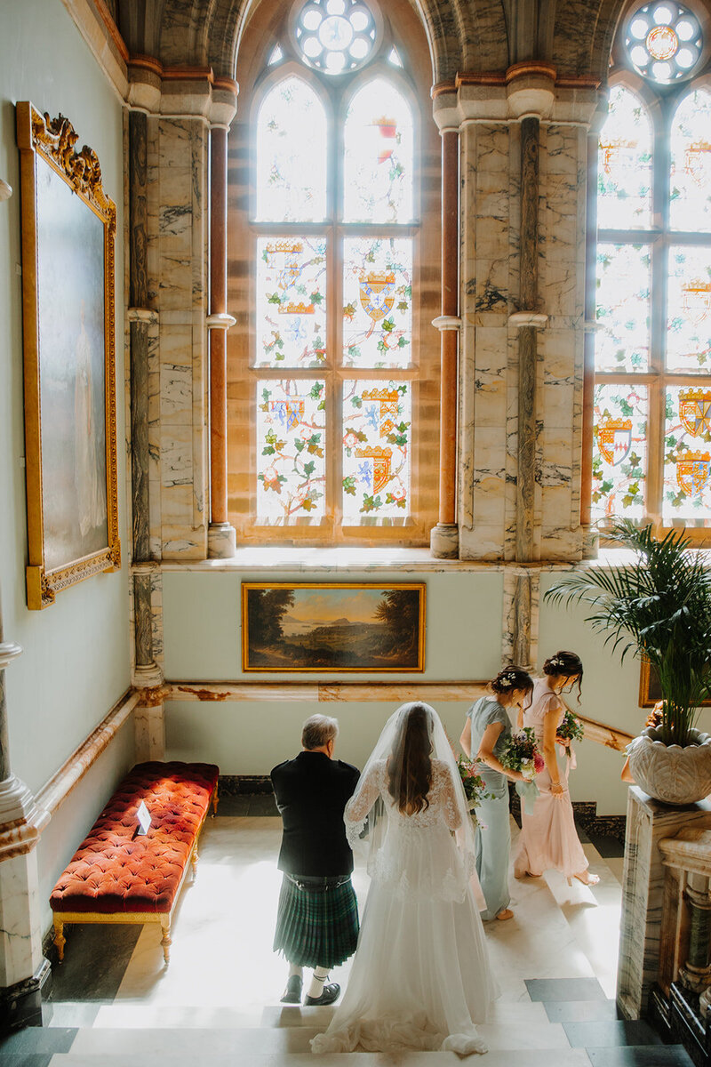a bride descends a staircase with her bridal party at Mount Stuart House 