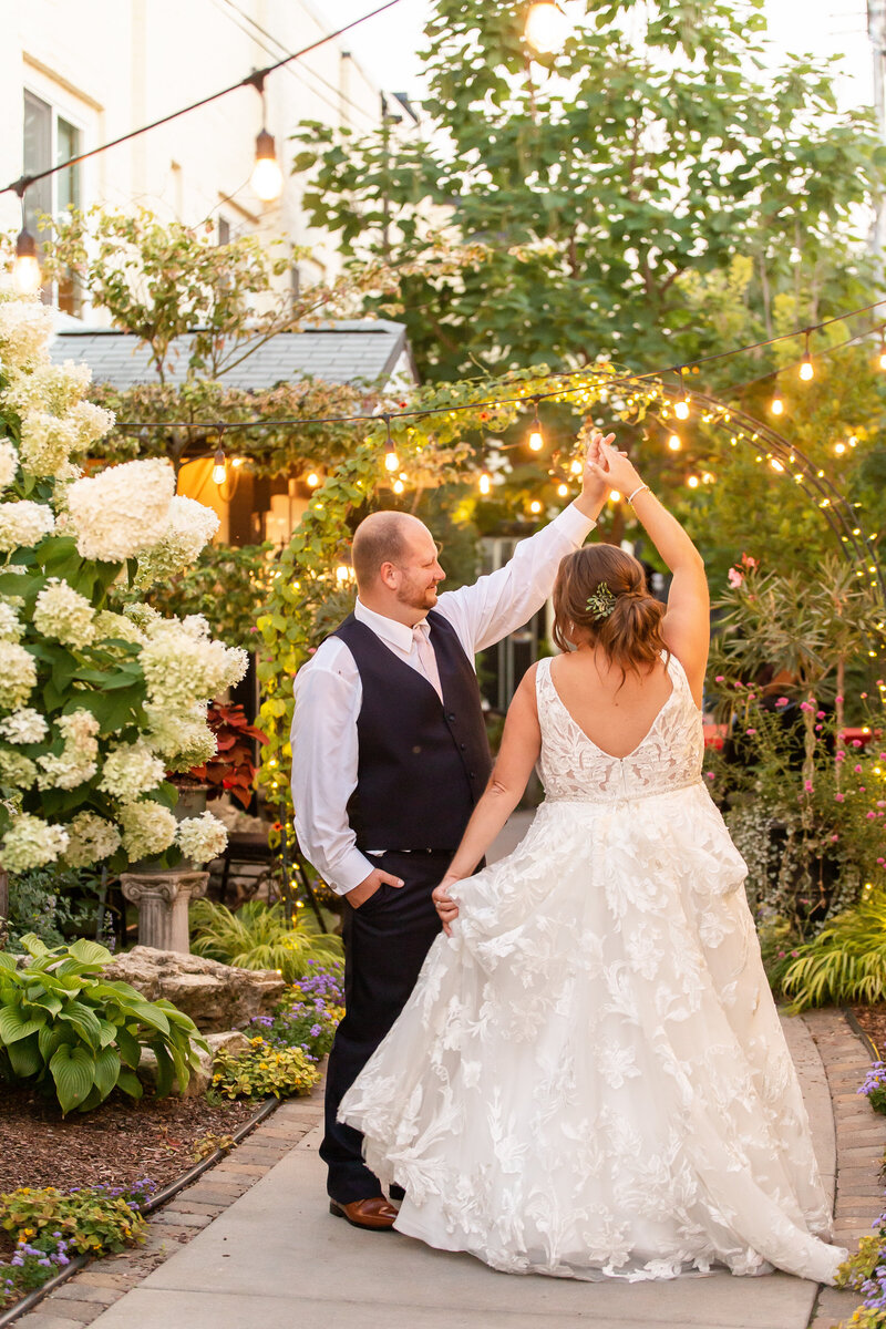 A white couple is dancing and twirling in a colorful outdoor garden