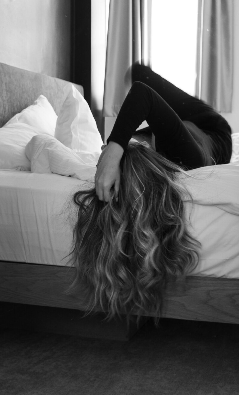editorial photo of woman laying on bed with her hair down in black and white editing