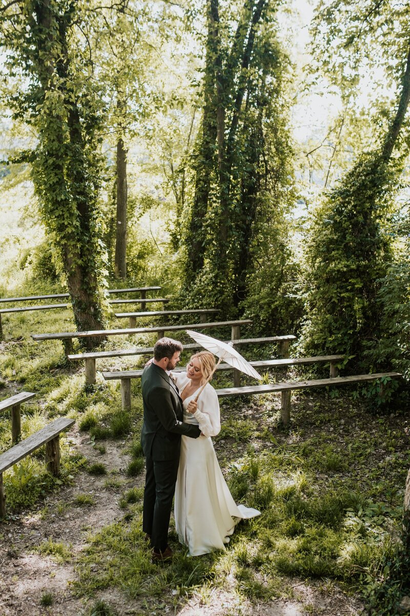 a bride and groom embracing in a lush green area