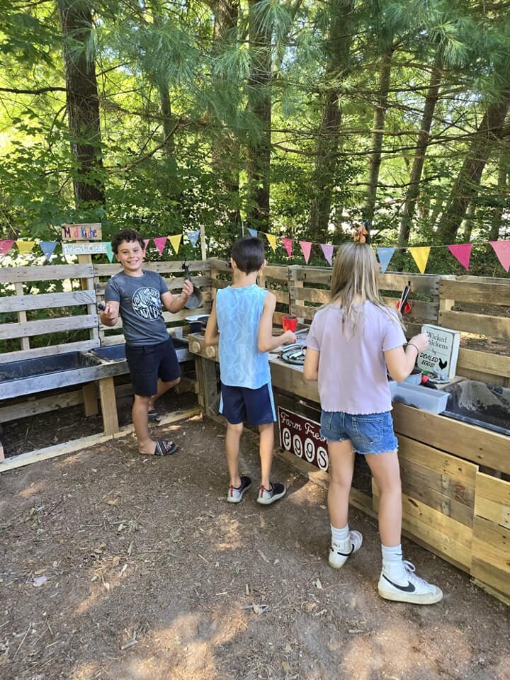 4 kids and 2 adults tending to a growing green garden. 