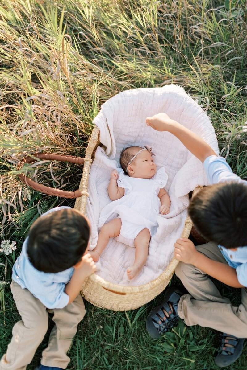 Two brothers holding their new baby sister in a loving portrait, captured by Emily Barbara, a family photographer in Milwaukee.