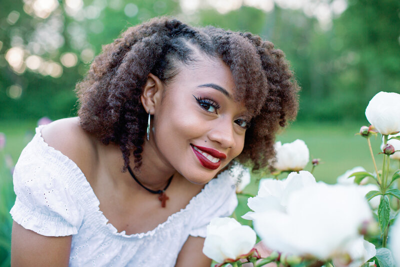 Photo taken by Monette Wagner Photography of high school senior girl posing next to white flower at Holcomb Gardens in Indianapolis