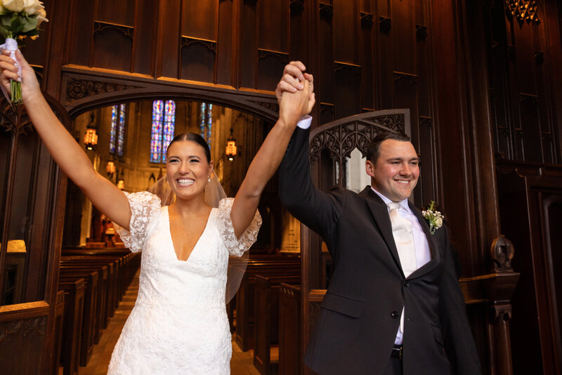 Bride and groom hold hands as they are welcomed by family and friends as they exit Heinz Chapel on their wedding day. Photo taken by Aaron Aldhizer