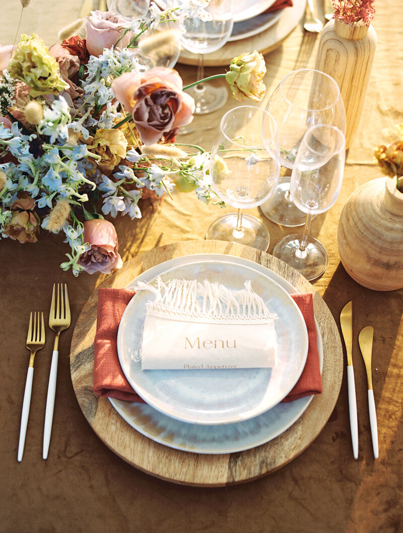 Neutral and gold wedding tablescape with wood charger, rust napkin, floral centerpiece, and glassware | Ohio wedding photographer