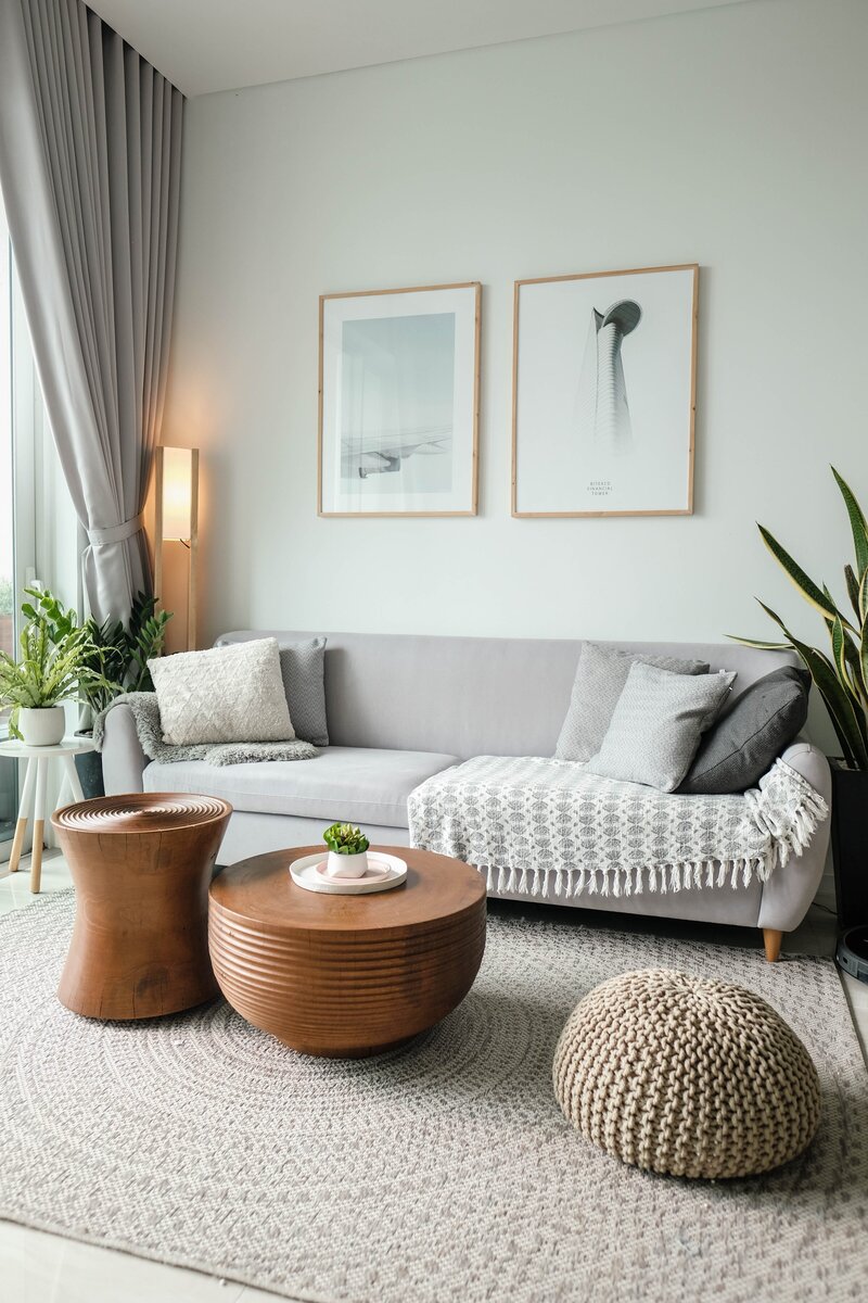 gray couch with pillows, plants, and tables surrounding it