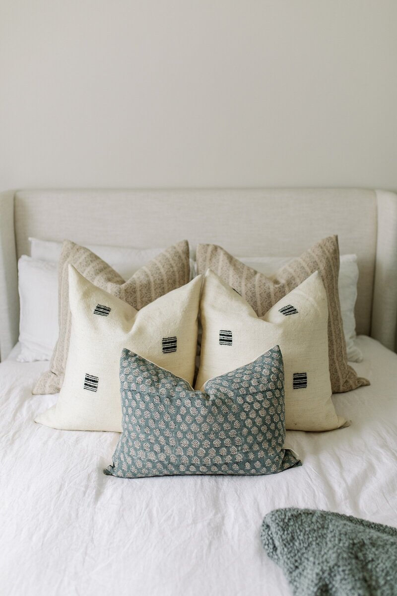 Bedroom study corner with fluffy cream chair, rust pillow, gold lamp, and foot cushion in Encinitas, California.